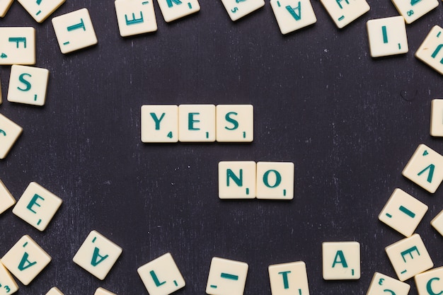 Letters yes or no made from scrabble game letters against black background