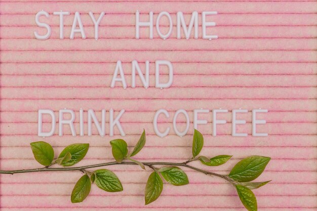 Photo lettreing booard with quote stay home and drink coffee decorated with spring branch with green fresh leaves spring motivation background