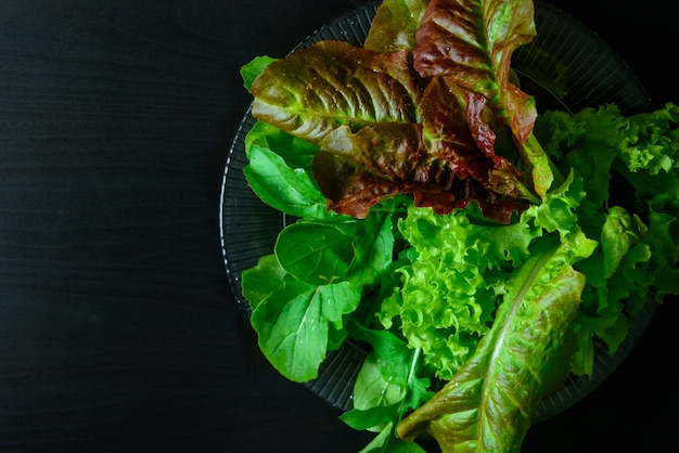 Lettuce and arugula leaves on black wooden table, organic food, vegetarianism.