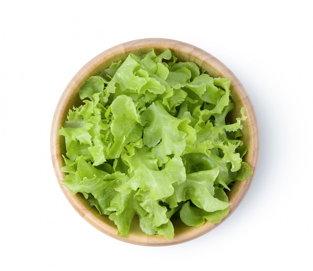 Lettuce leaves in wood bowl on white wall. 