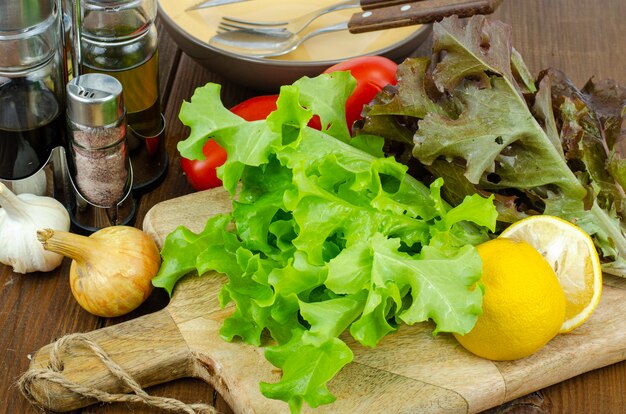 Lettuce leaves on wooden cutting board, set of spices for cooking. Studio Photo.