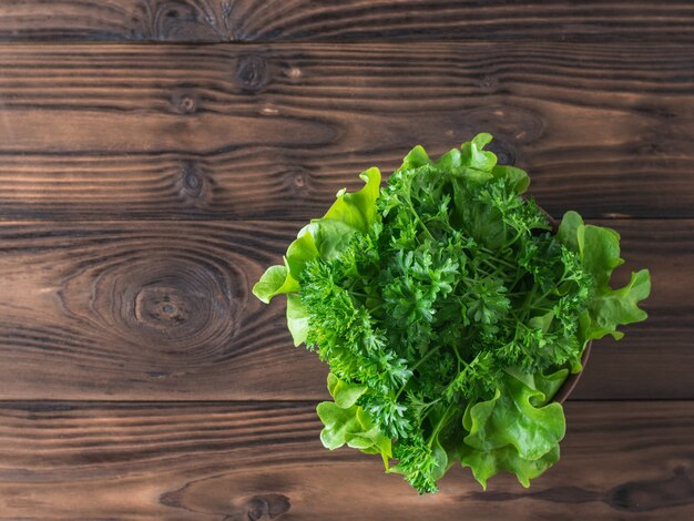 Lettuce and parsley in a bowl on a wooden table with a fork