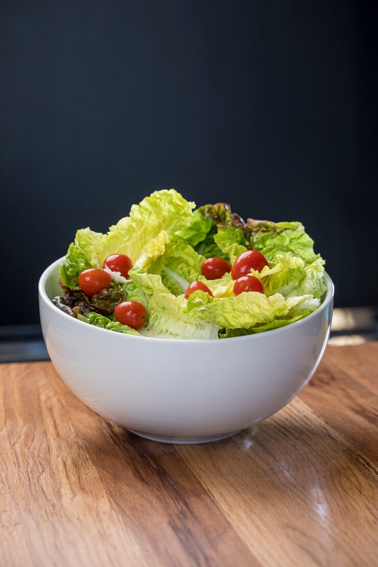 Photo lettuce salad and cherry tomatoes in white bowl on wooden table