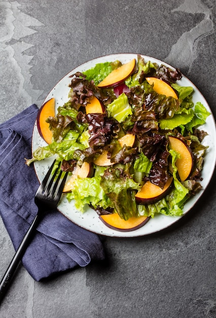 Lettuce salad with plums, slate background.