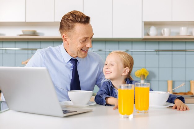 Leuk aardig positief meisje dat samen met haar vader zit en naar laptop scren kijkt