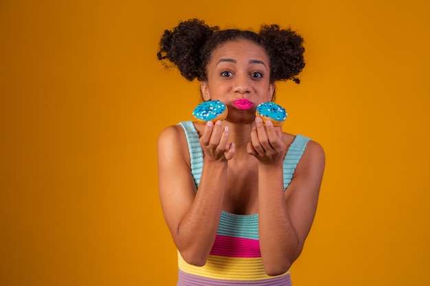 Leuk afromeisje dat twee kleurrijke donuts houdt. Afro vrouw met donuts