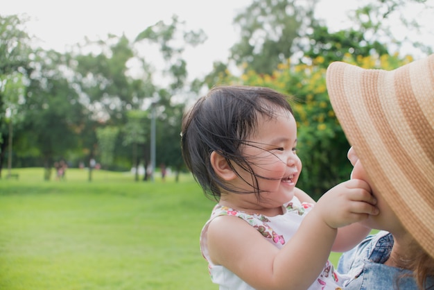 Leuk Aziatisch babymeisje dat gelukkig voelt terwijl het spelen in openbaar park met haar moeder.