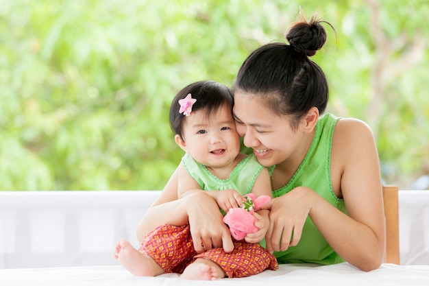 Leuk Aziatisch babymeisje die en met haar moeder en schildpadpop glimlachen spelen