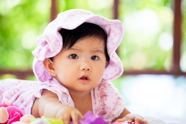 Leuk Aziatisch babymeisje draagt ​​roze hoed die op deken op groene aardachtergrond kruipen