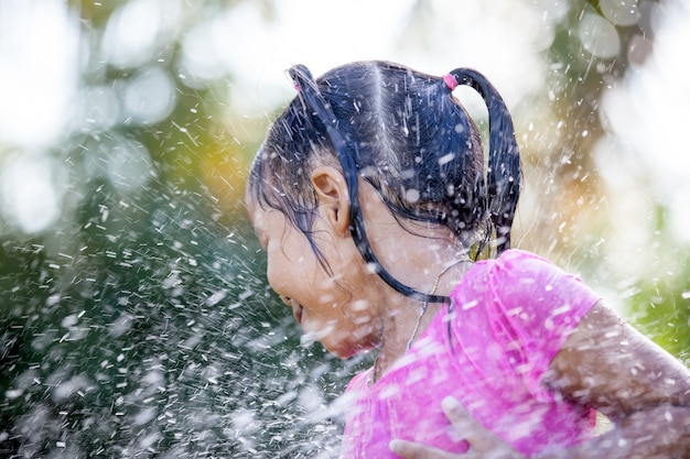 Leuk Aziatisch kindmeisje die pret hebben om te baden en waterplons in buitenkant te spelen