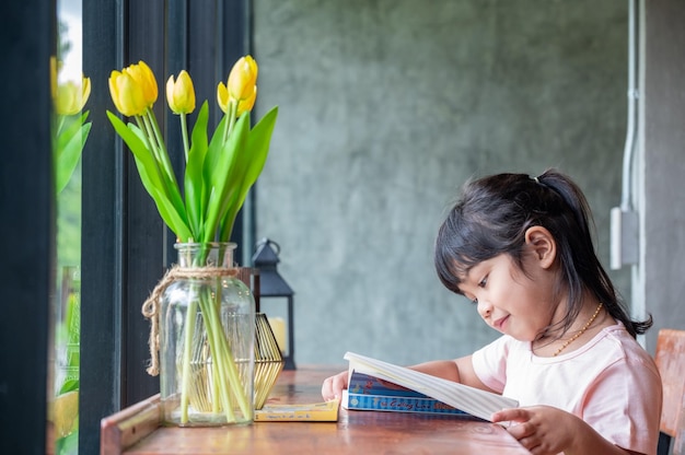 Leuk Aziatisch meisje dat een boek leest dat op een houten tafel zit gelukkig leven cocept