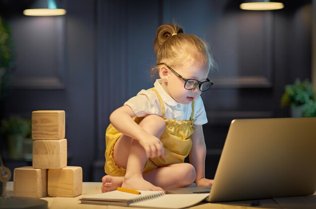 Leuk babymeisje dat aan een computer thuis werkt.