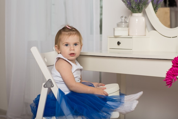 Leuk babymeisje die op haar gedachtengang in een witte slaapkamer met een ronde spiegel letten