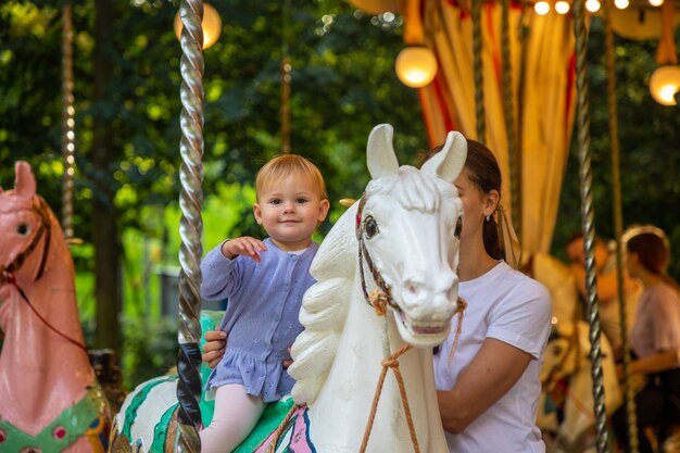 Leuk babymeisje met moeder op het paard van oude retro carrousel Praag Tsjechië