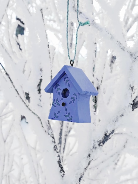 Leuk decoratief vogelhuisje hangend aan besneeuwde takken