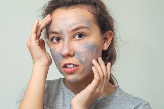 Leuk en gelukkig meisje met een cosmetische gezichtsmasker