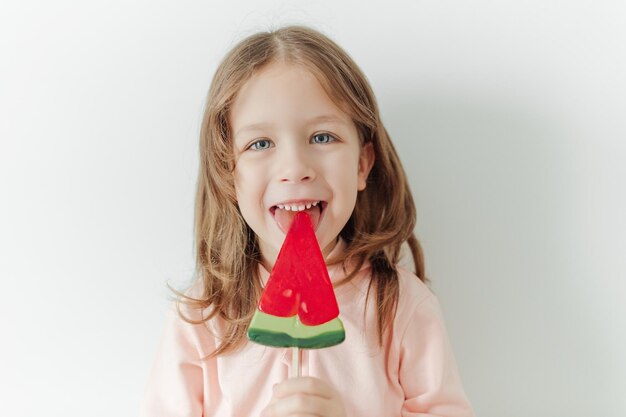 Leuk gelukkig en positief meisje met watermeloenlolly witte achtergrond vakantie