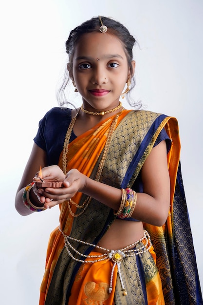 Leuk indisch maharashtriaans klein meisje dat de lamp in de hand houdt en het traditionele festival raksha bandhan of diwali . viert