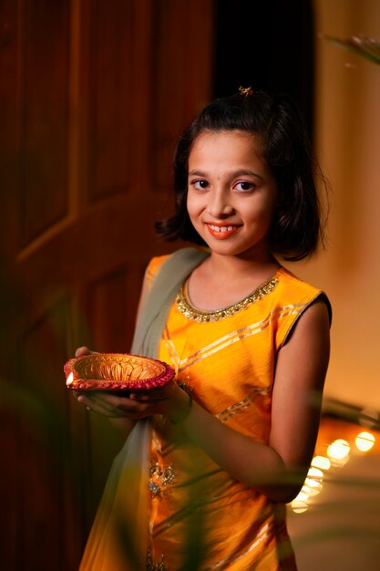 Leuk Indisch meisje dat diya of olielampen vasthoudt voor Diwali-viering.