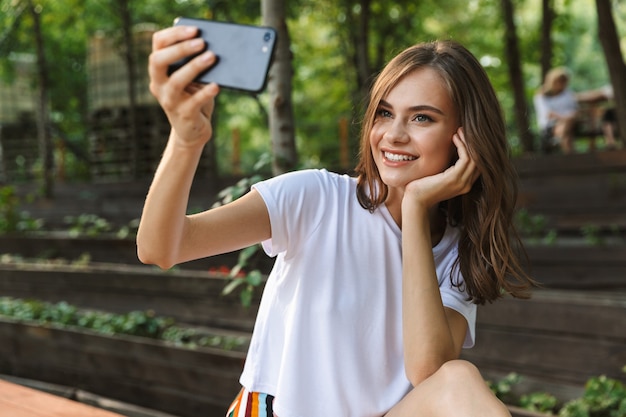 Leuk jong meisje dat een selfie met mobiele telefoon neemt in het park buiten