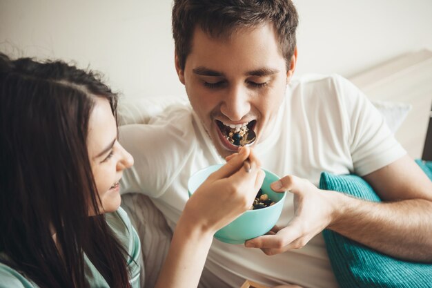 Leuk Kaukasisch paar dat granen in bed vroeg in de ochtend omhelst en samen glimlacht