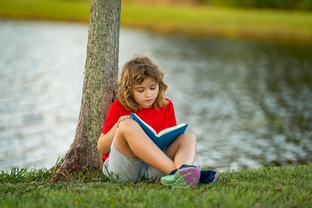 Leuk kind dat boek leest op de weide buiten school en onderwijs natuur en park vroeg leren weinig