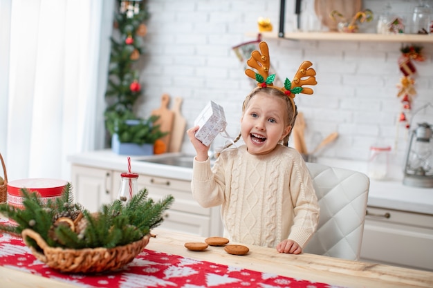 Leuk kind in lichte sweater en hoofdband met zittende hertengeweien