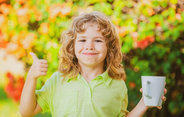 Leuk kinderportret met mokkind dat een grote kop met kruidenthee vasthoudt Gelukkige kinderjaren