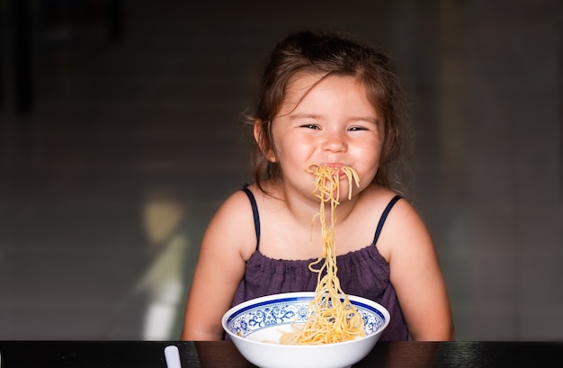 Leuk kindmeisje dat spaghetti eet en glimlacht