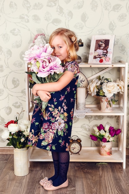 Leuk klein kindmeisje met de lentebloemen, gelukkig babymeisje met mand van bloemen.