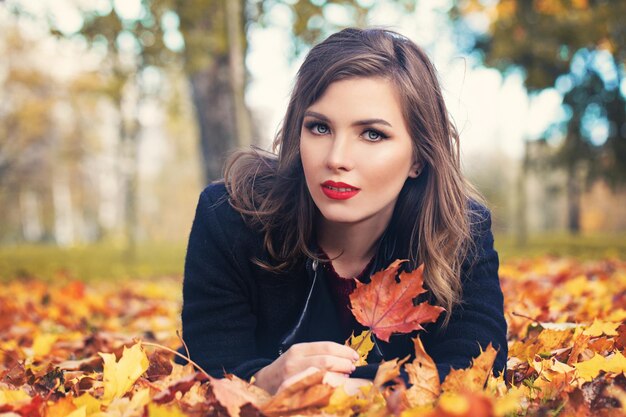 Leuk meisje buitenshuis. Mooie vrouw mannequin met herfstbladeren