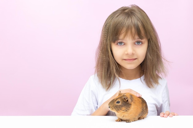 Leuk meisje dat een proefkonijn houdt. Geïsoleerd op roze achtergrond.