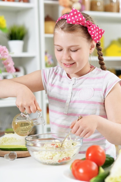 Leuk meisje die heerlijke verse salade in keuken voorbereiden