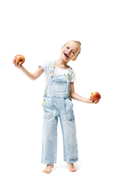 Leuk meisje gekleed in denim overall met appels op een witte achtergrond