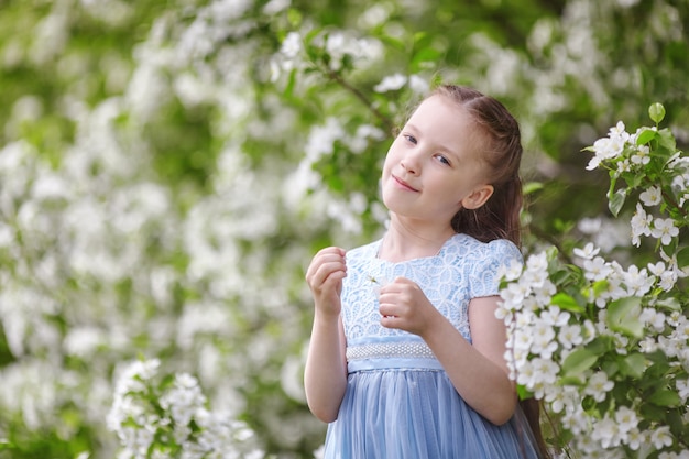 Leuk meisje in de bloeiende tuin van de appelboom bij de lente