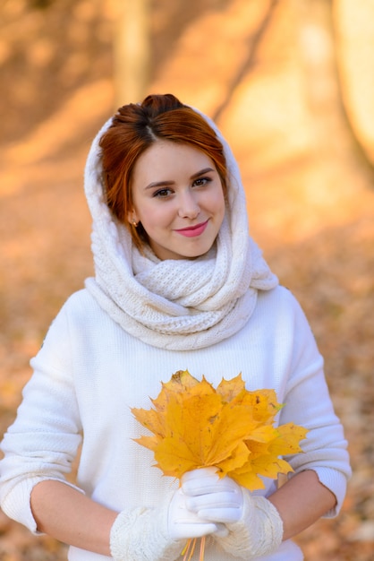 Leuk meisje in lange witte trouwjurk onder herfst bomen