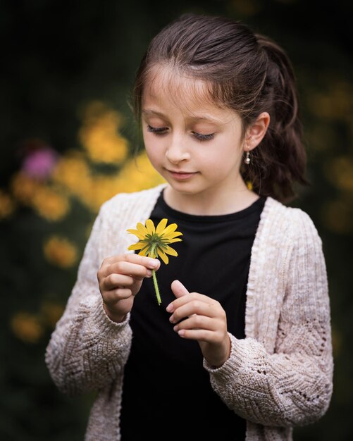 Foto leuk meisje met een bloem terwijl ze buiten staat.