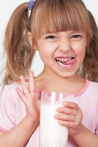 Leuk meisje met een glas melk op een lichte achtergrond.