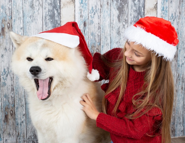 Leuk meisje met een hond met kerstmutsen