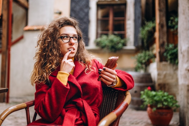 Leuk meisje met krullend haar die telefoon met behulp van openlucht