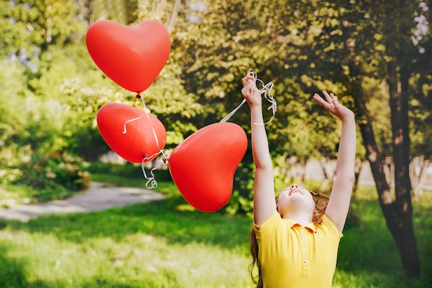 Leuk meisje met rode ballonnen op buitenshuis.