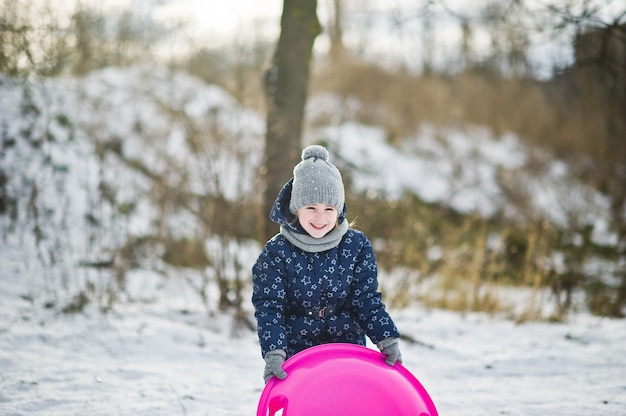 Leuk meisje met schotelsleeën in openlucht op de winterdag.