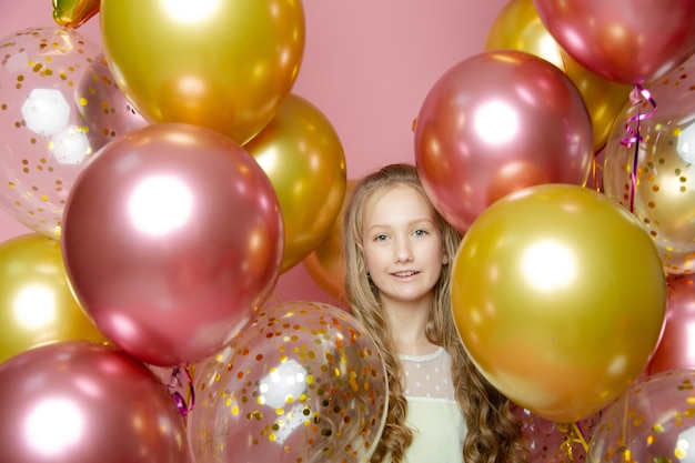 Leuk meisje op een roze achtergrond met ballonnen