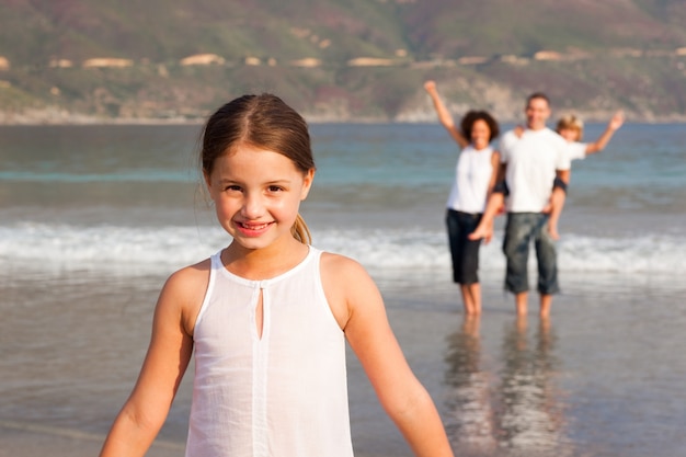 Leuk meisje op een strand met haar ouders en haar broer op achtergrond