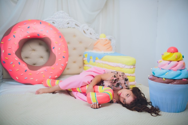 Leuk meisje poseren met roze donuts, gek rond, dessert, slecht eten, kijkt in het gat in de donut, houdt donuts bij de ogen