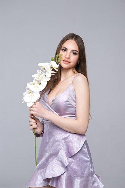 Leuk modelmeisje in jurk met orchideebloem Portret met een mooi gezicht voor reclame voor schoonheidsspecialisten en make-up