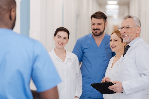 Leuk om je te ontmoeten. Vriendelijke glimlachende bekwame kinderartsen die genieten van vrije tijd in de hal van de kliniek en interesse tonen terwijl ze kennis maken met een nieuwe jonge collega