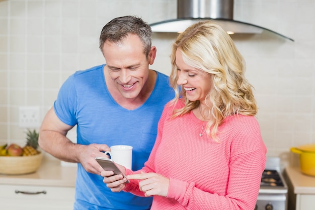 Leuk paar die smartphone in de keuken bekijken