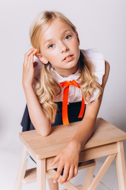 Leuk schattig Kaukasisch blondie meisje in schooluniform op witte achtergrond