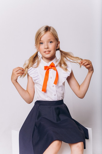 Leuk schattig Kaukasisch blondie meisje in schooluniform op witte achtergrond